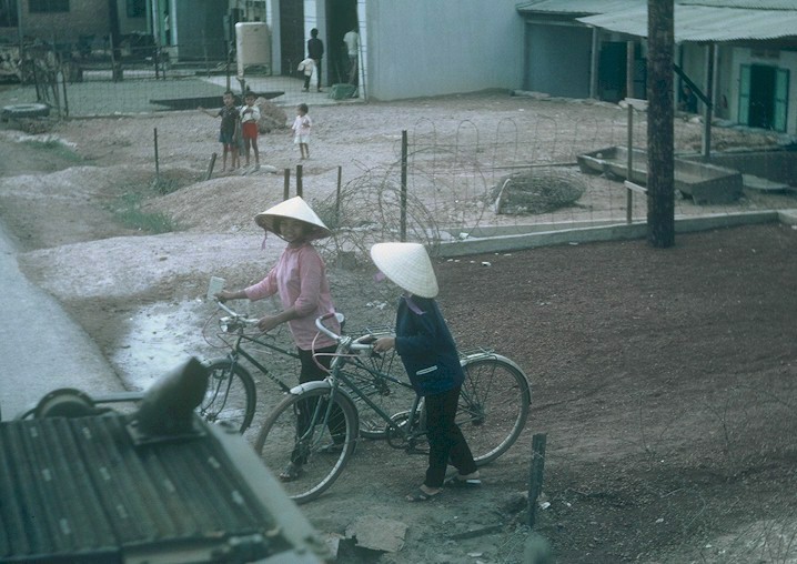Two girls with bicycles wait for us to pass by.
